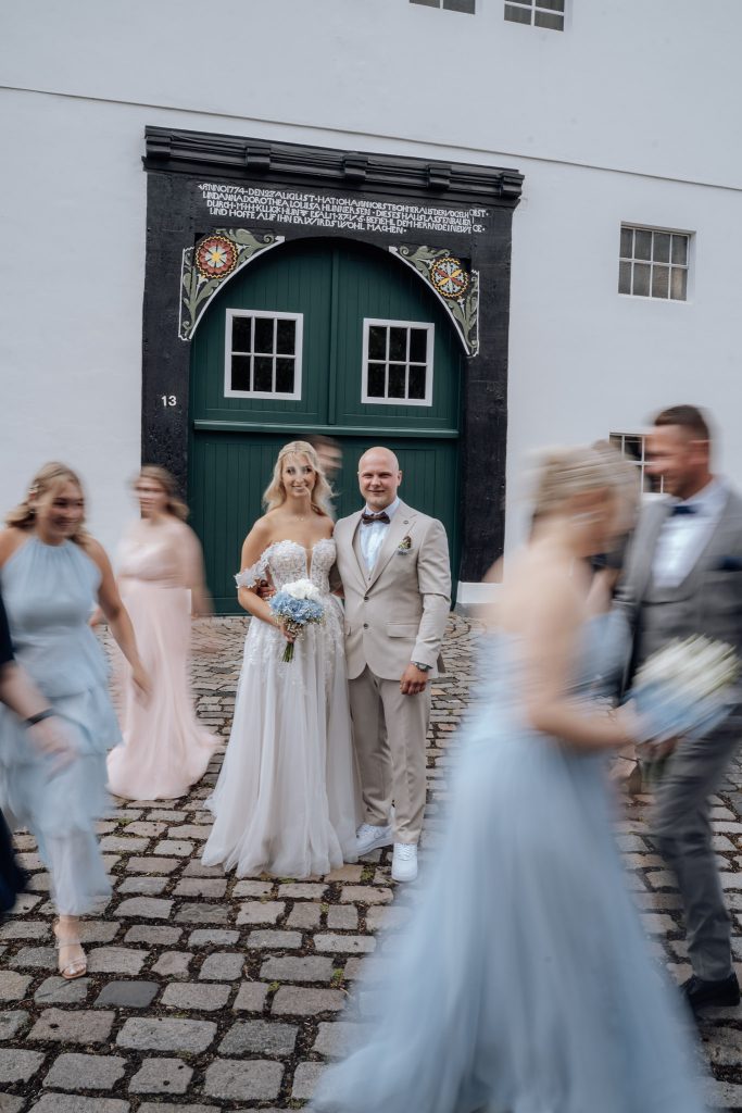 Fröhliches Gruppenfoto mit Brautpaar und engem Freundeskreis