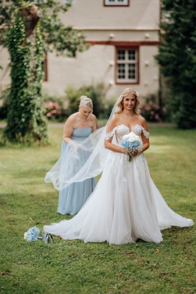 Braut nähert sich dem Bräutigam beim First Look im Garten