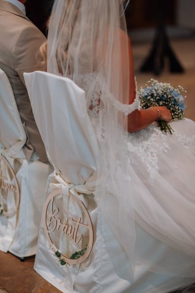 Detailaufnahme von Brautkleid und Brautstrauß während der Trauung